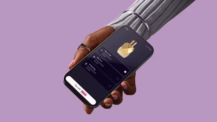 A hand holding a smartphone displaying the Klarna app with the text "Shop your way with Klarna"